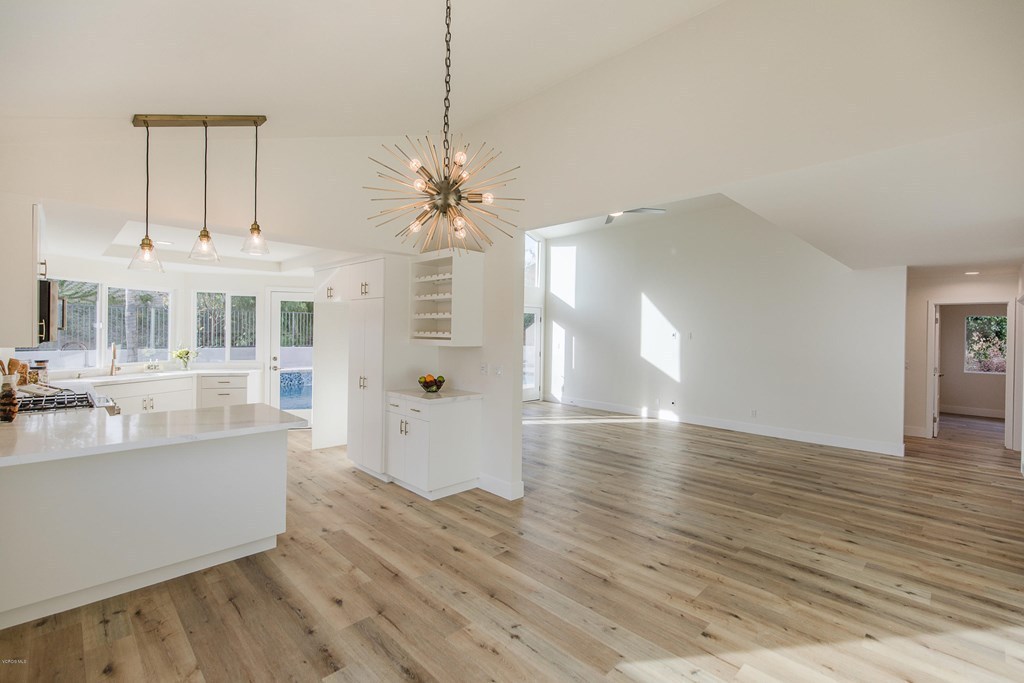 Open plan kitchen and living area after a whole home interior remodel, with a quartz island, white cabinetry, and wide plank wood flooring